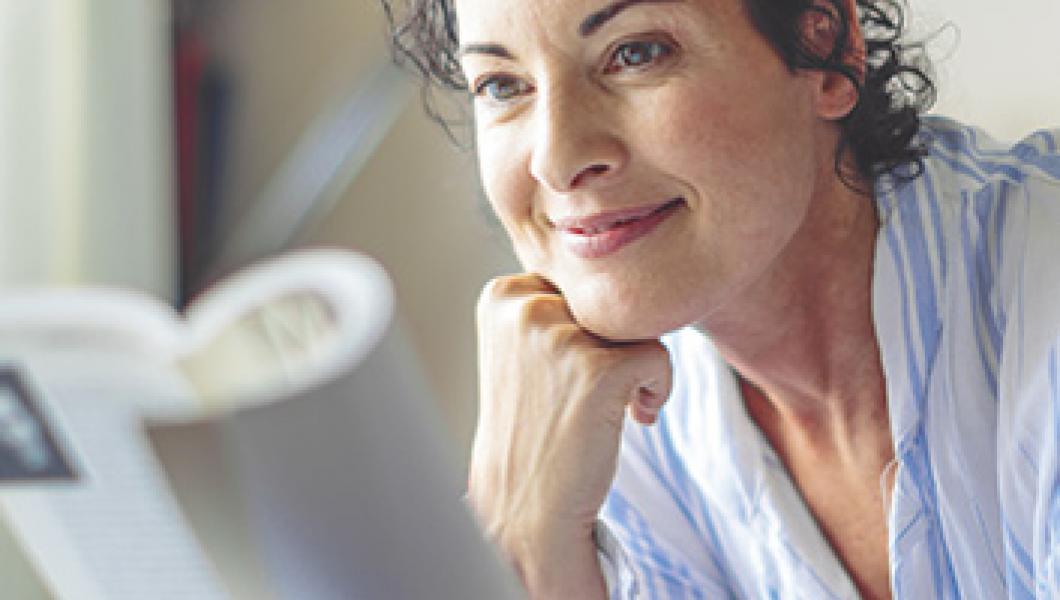 woman smiling reading a book in bed