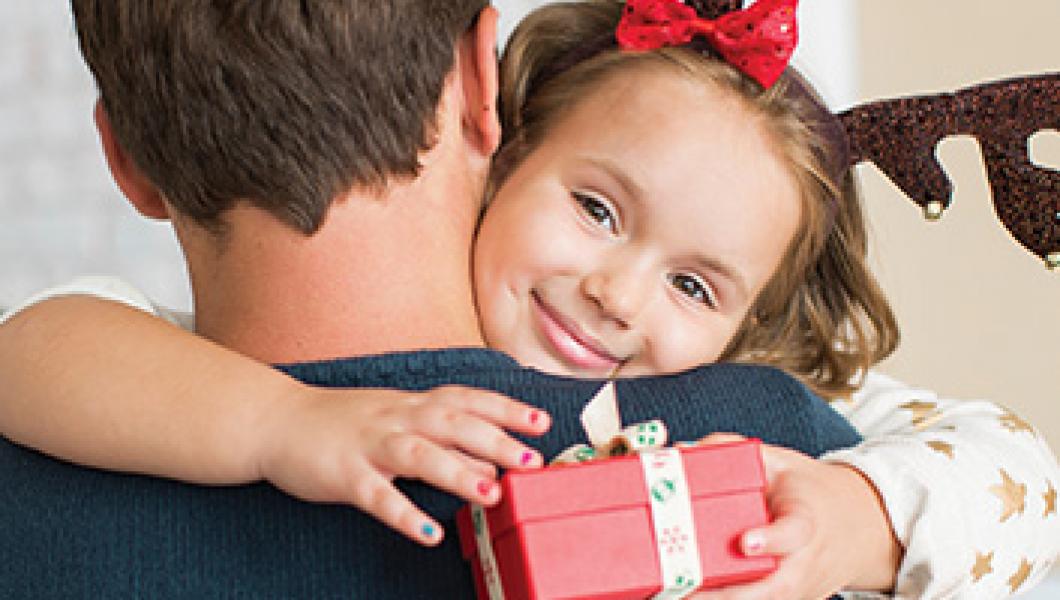 father holding smiling daughter with gift box