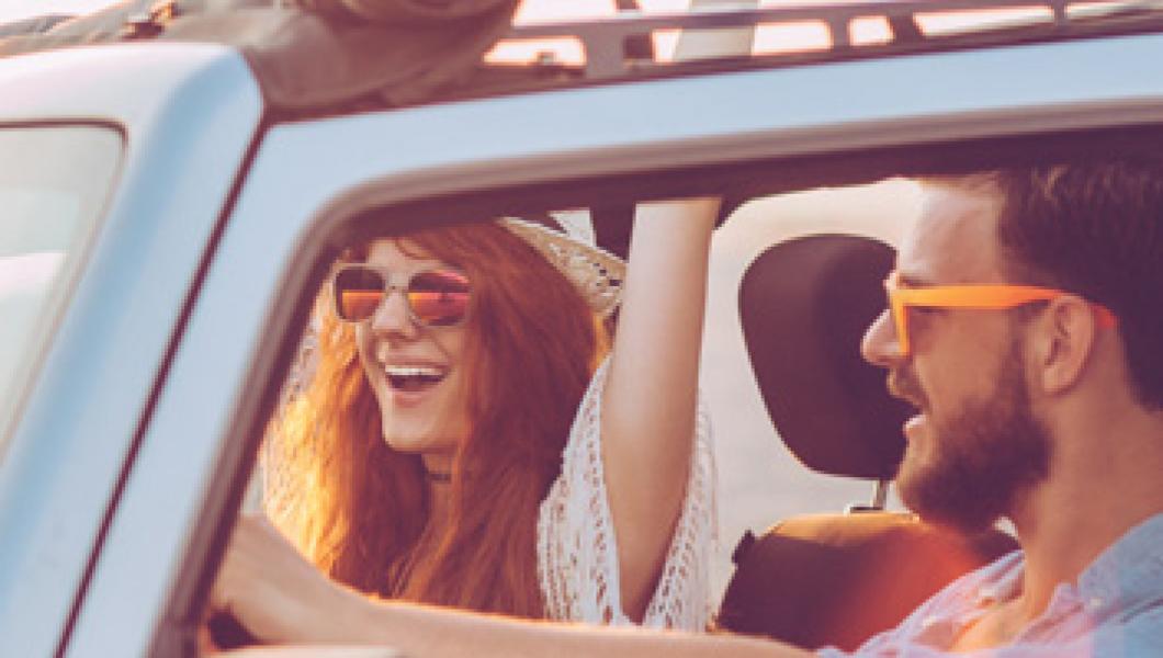 man and woman driving in convertible wearing sunglasses