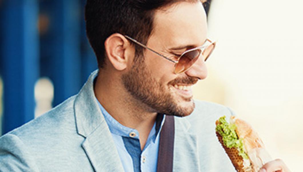 man eating a sandwich outside