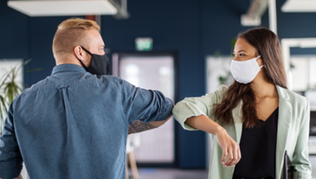 Coworkers bumping elbows and wearing masks