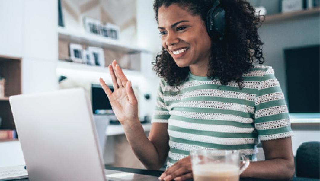 Woman smiling and waving to a person on her computer