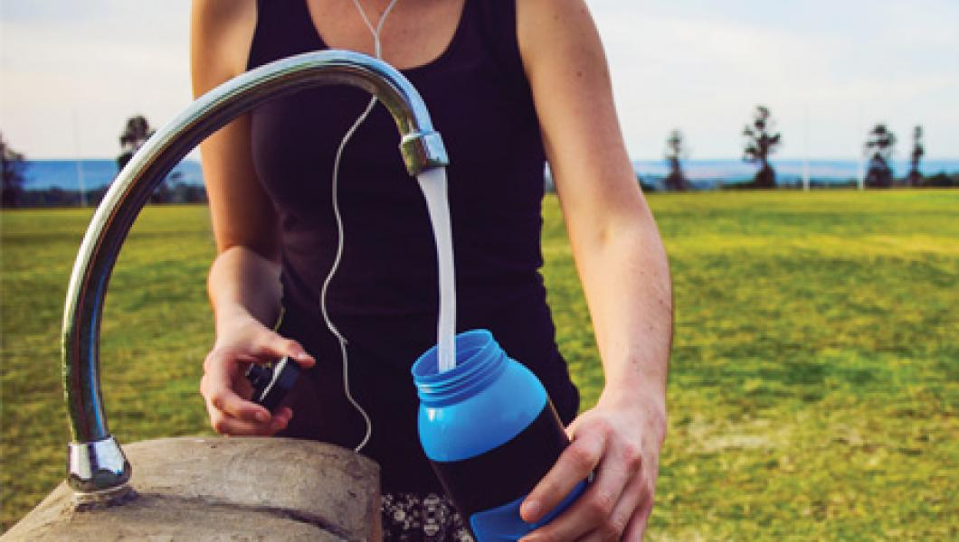 A woman fills a water bottle with fresh water