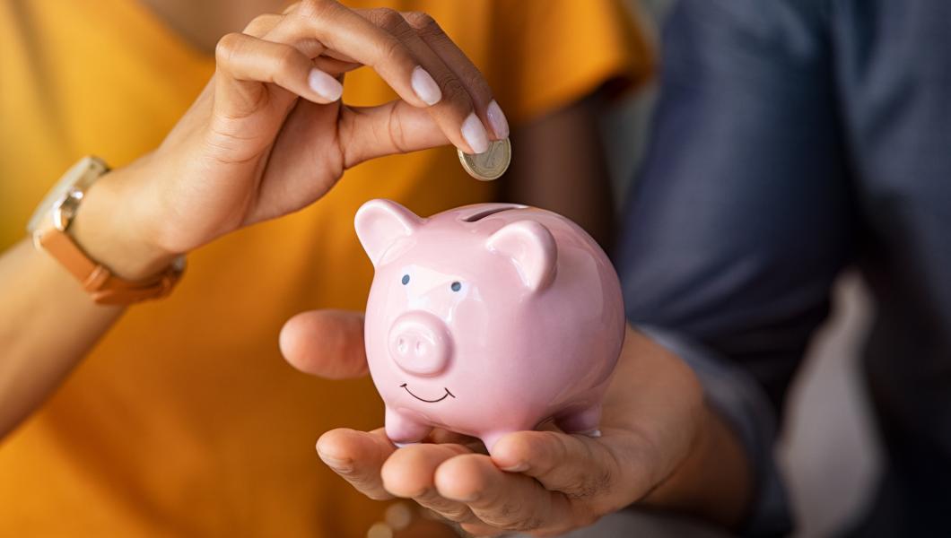 hands placing coin into piggy bank