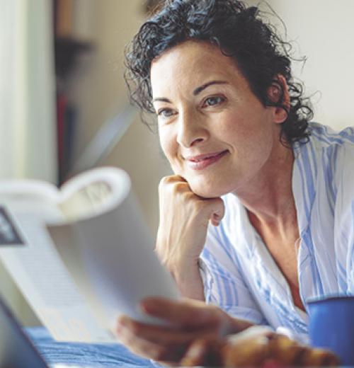 woman smiling reading a book in bed