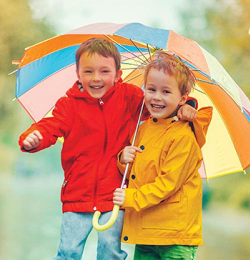 two young boys smiling under umbrella