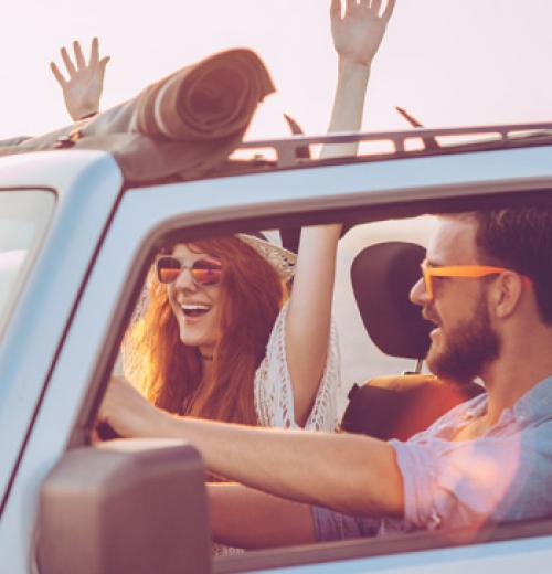 man and woman driving in convertible wearing sunglasses