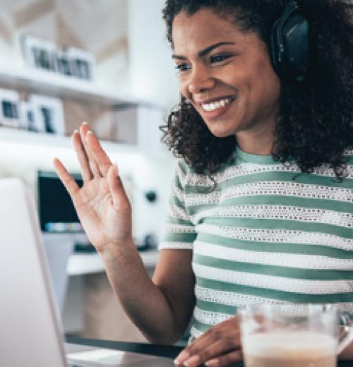 Woman smiling and waving to a person on her computer