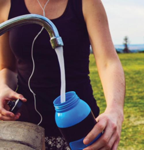 A woman fills a water bottle with fresh water