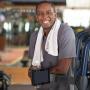 man at gym with leaning on exercise equipment smiling